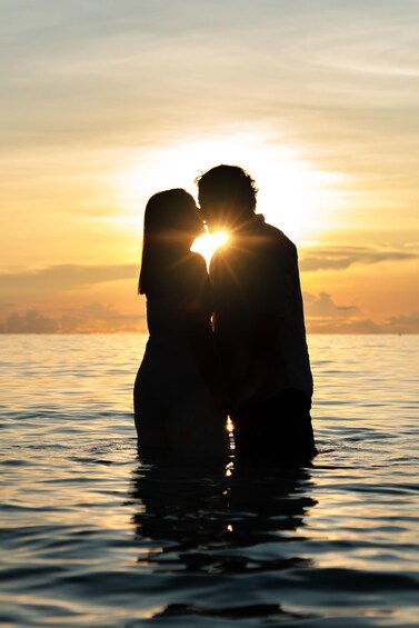 A couple embracing in silhouette against a sunset over water. 5