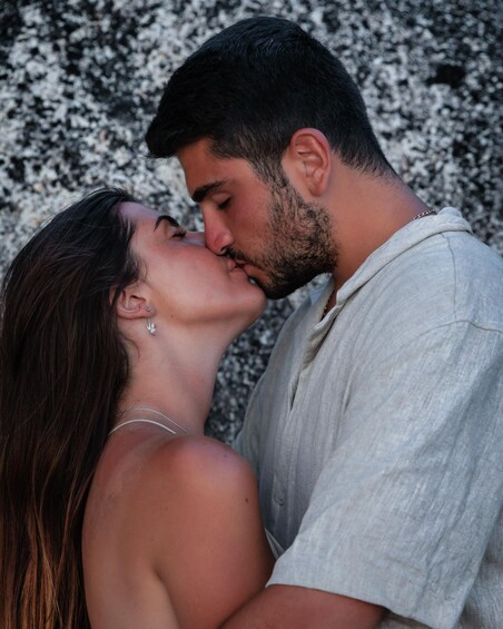 A couple embracing in front of a textured stone wall. 3