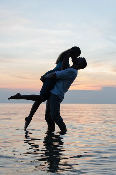 A couple embracing in shallow water during sunset. 2