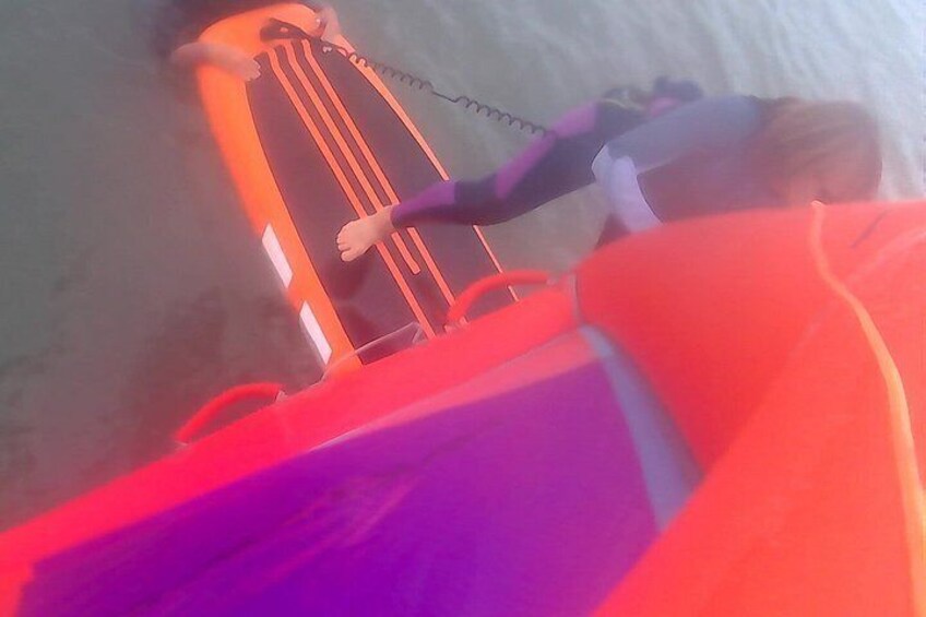 A person lying on a surfboard in a body of water. 2