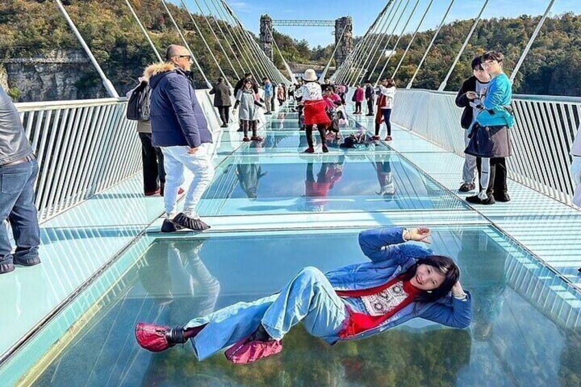 A glass-bottomed bridge with people walking and lying on it. 5