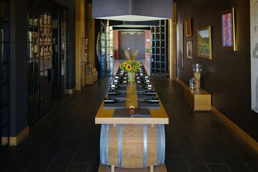 A long table with bottles lined up in the center, flanked by shelves with books and framed pictures on the walls. 5
