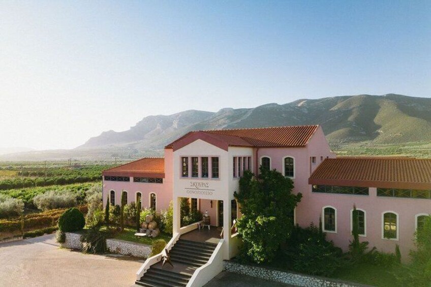 A pink building with a red roof, surrounded by greenery and mountains in the background. 2