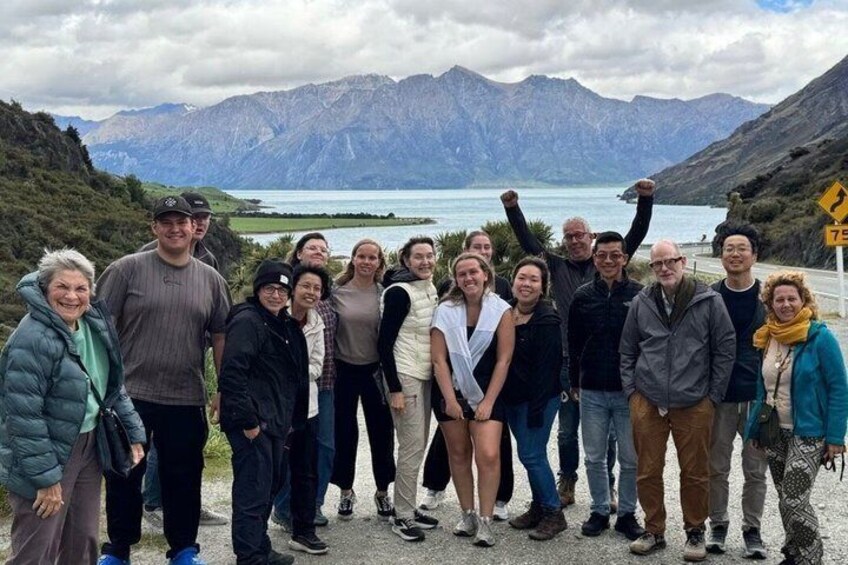 A group of people standing on a path with a mountainous landscape and a lake in the background. 3