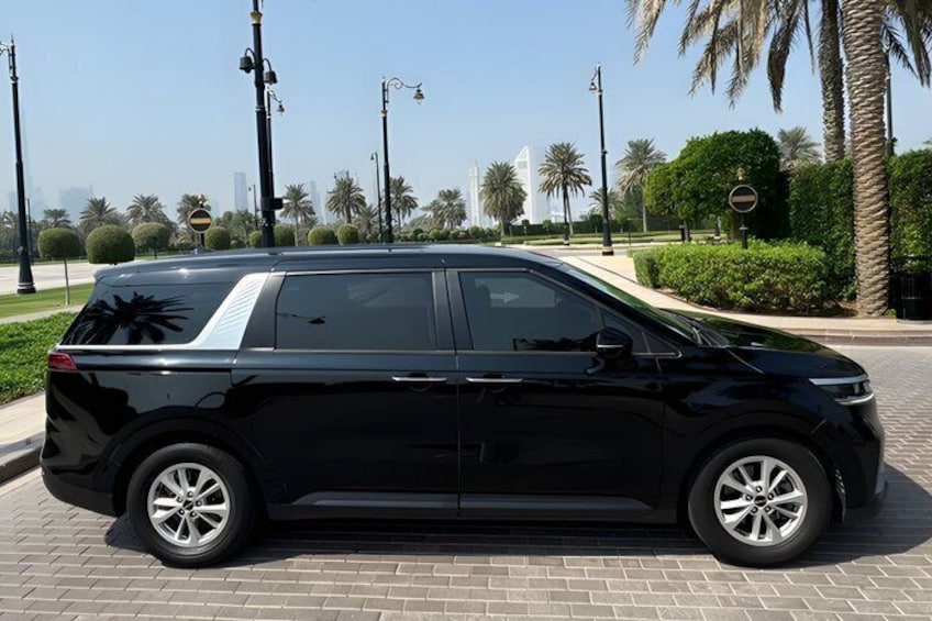 A black SUV parked on a paved area with palm trees and a clear sky in the background. 5