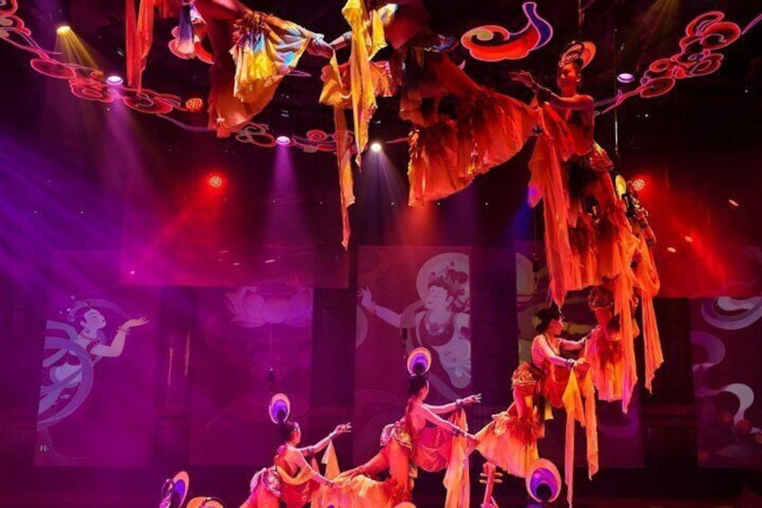 A performance with dancers in traditional costumes, suspended fabric, and stage lighting. 2