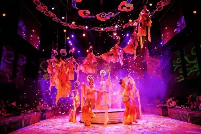 A stage with performers in traditional costumes, a circular platform, and hanging decorations. 1
