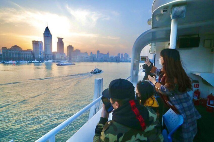 A river with a city skyline in the background, a boat, and people taking photos. 3