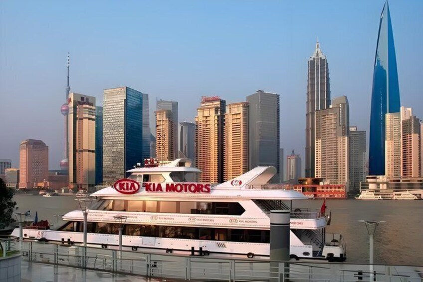 A white yacht with 'KIA Motors' branding, docked near a city skyline with modern skyscrapers. 5