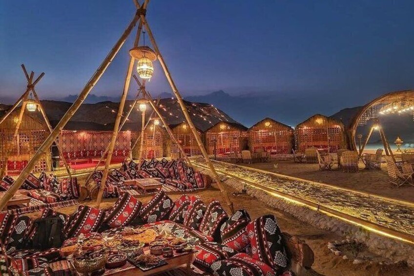 A traditional yurt campsite at dusk with yurts, colorful textiles, and a paved path. 1