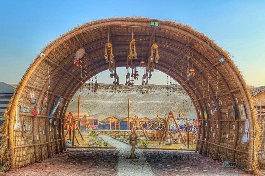 A traditional structure with a thatched roof, a central fire pit, and surrounding wooden benches. 2
