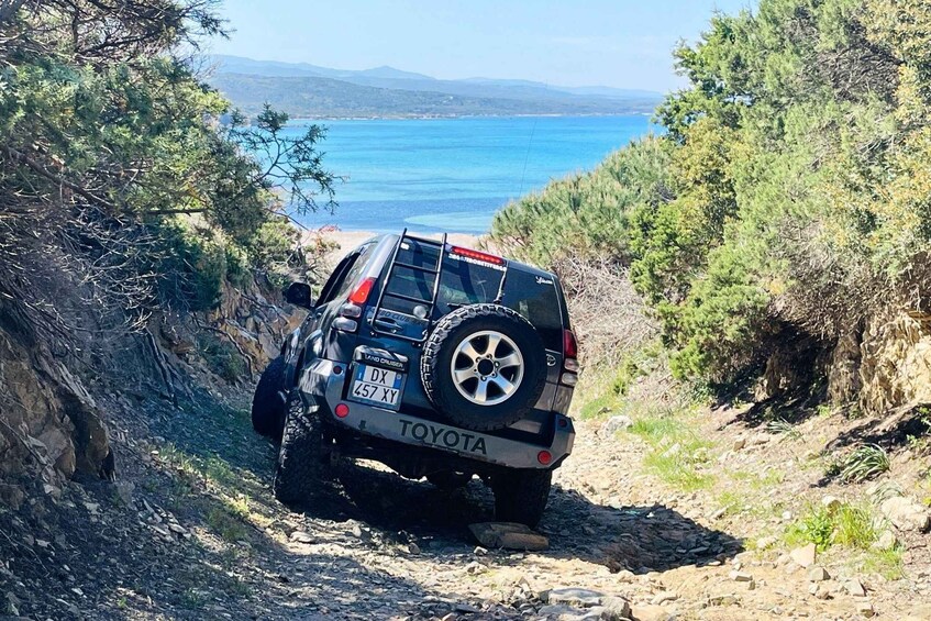 A Toyota off-road vehicle on a rocky path with a coastal view in the background. 1