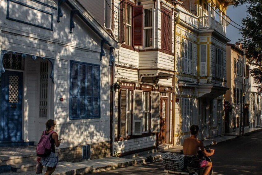 A street with buildings, a person on a bicycle, and a person walking. 2