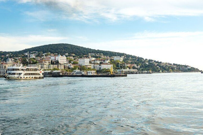 A calm river with a boat, a pier, and a hillside with buildings. 1