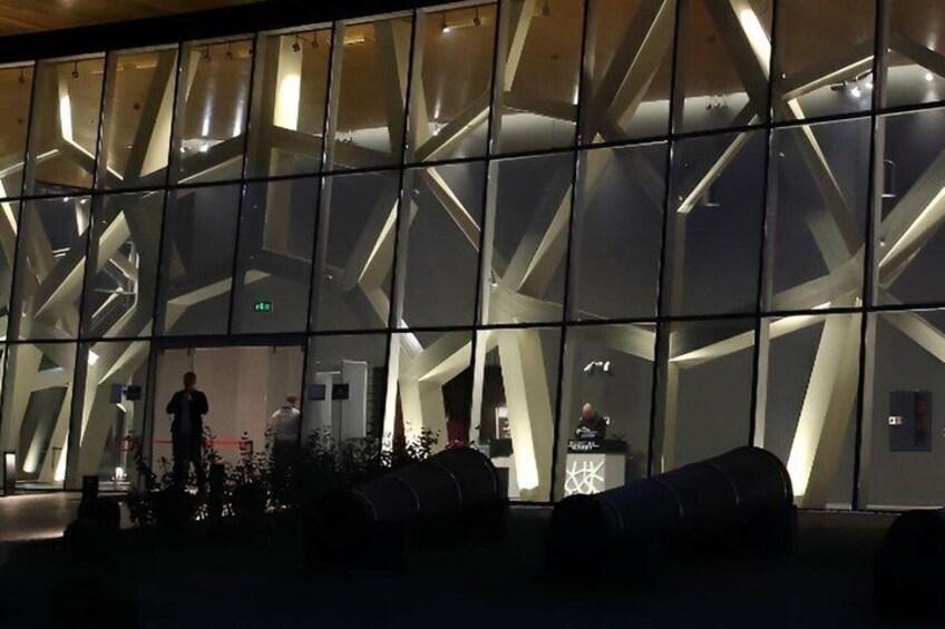 A modern building with a geometric facade and a person standing near the entrance. 1