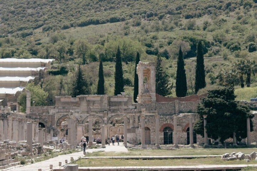 Ancient ruins with columns and arches, surrounded by trees and a hilly landscape. 3