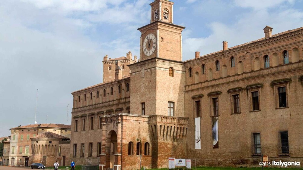 A historic building with a clock tower, arched windows, and a banner. 1
