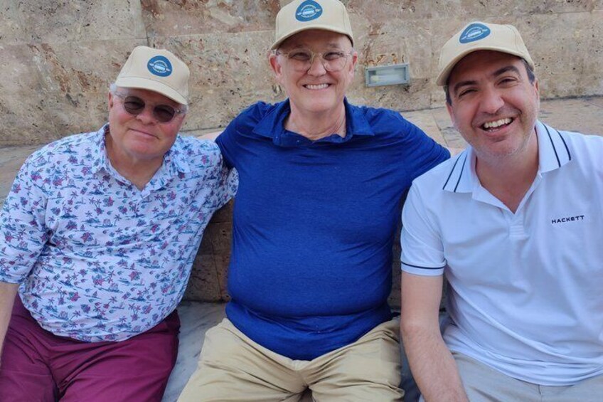 Three people sitting against a stone wall. 4