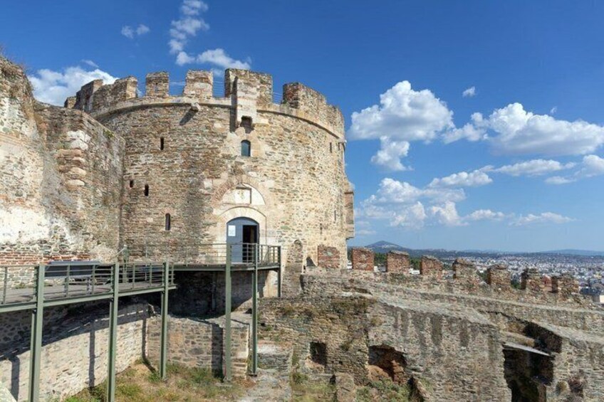 A historic stone castle with a central entrance, battlements, and a surrounding wall. 3