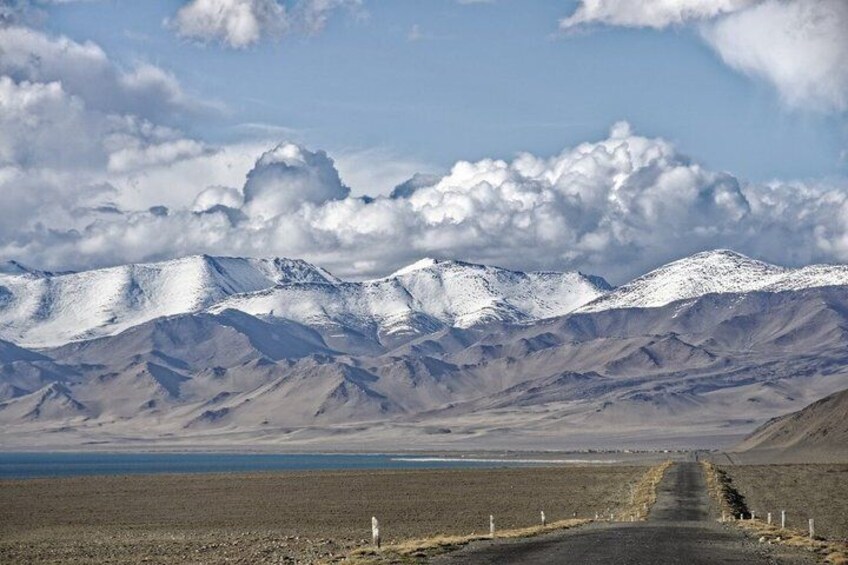 A road leading to snow-capped mountains with a clear sky. 4