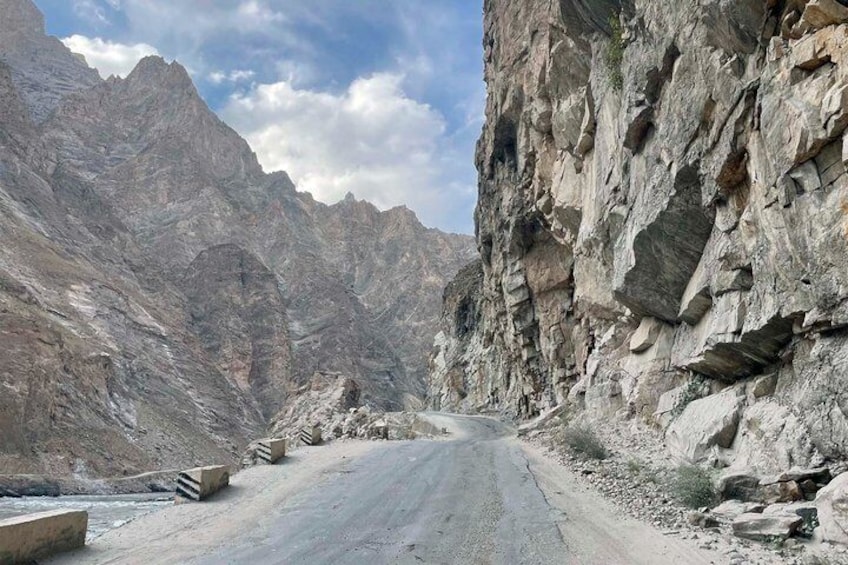 A narrow mountain road flanked by rocky cliffs. 1