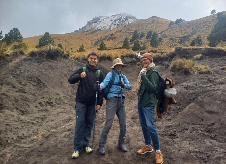 Three hikers on a dirt path with a mountain in the background. 1
