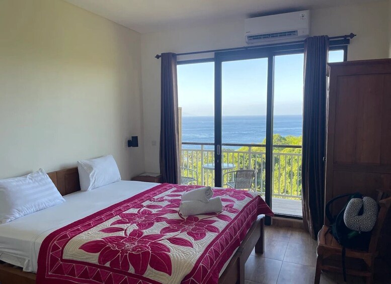 A bedroom with a bed, a balcony with a view of the ocean, and a chair. 4