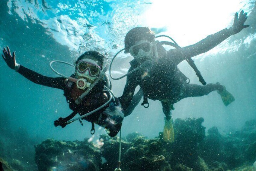 Two scuba divers underwater with fins, surrounded by marine life and coral. 3