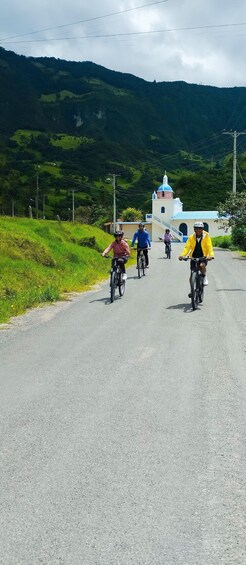 Cyclists on a paved road with a church in the background. 2