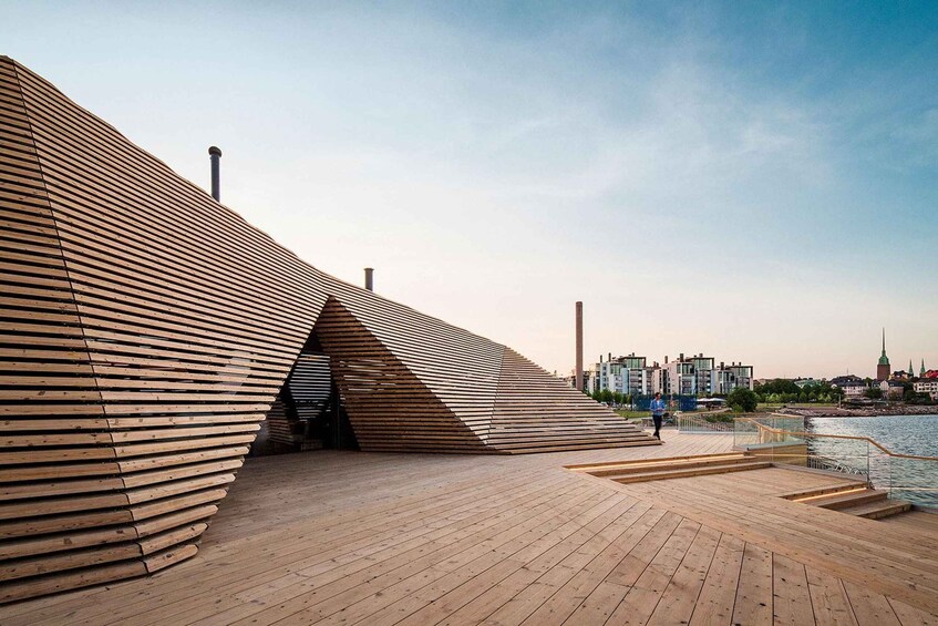 A modern wooden structure with a sloped roof, a wooden deck, and a river in the background. 2