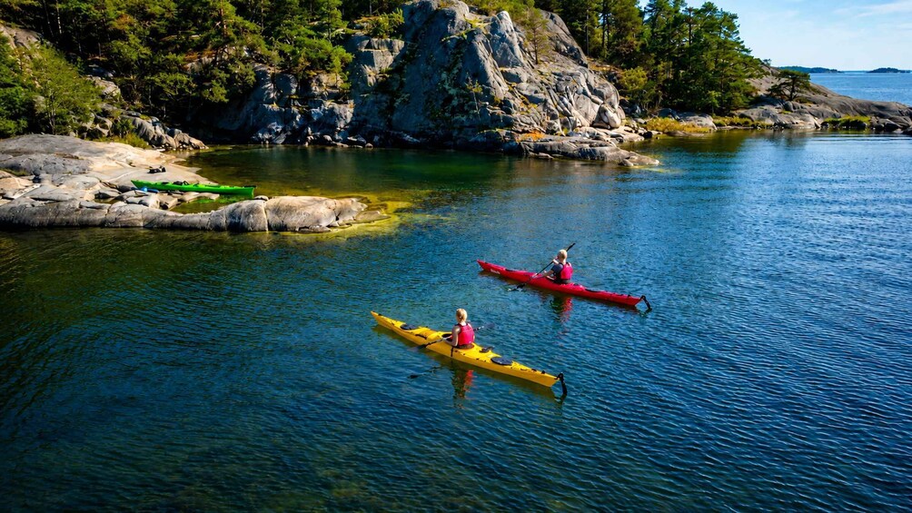Two kayaks on a calm lake surrounded by rocky shores and dense trees. 1