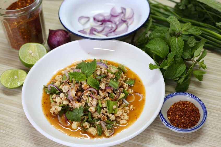 A bowl of Thai salad with ingredients like lime, red onion, and mint. 4