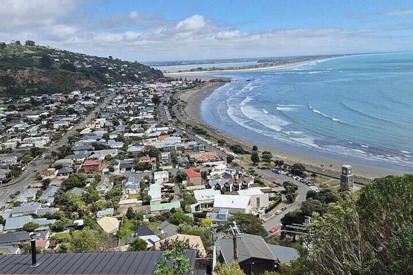A coastal town with houses along the beach, a clear sky, and a hilly landscape in the background. 2