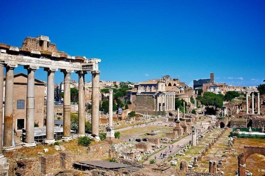 Ancient ruins with columns and a large building in the background. 5