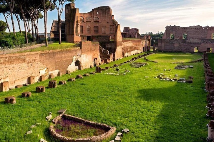 Ancient ruins with a grassy area and a circular stone structure. 4