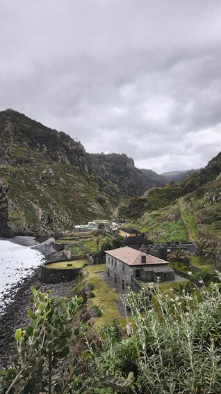 A coastal landscape with a stone building, a pathway, and lush greenery. 1