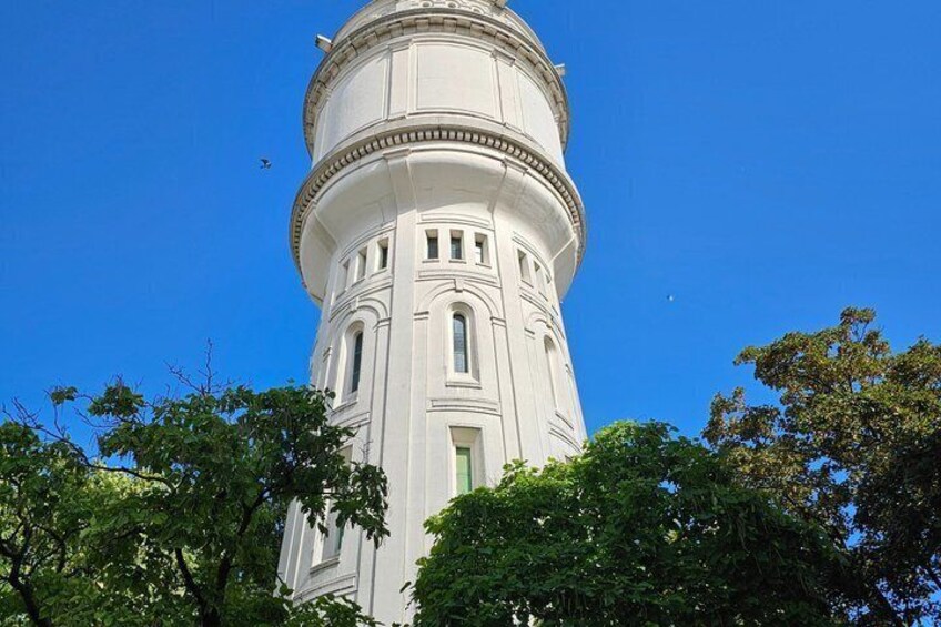 A white tower with a dome, surrounded by trees and a clear blue sky. 2
