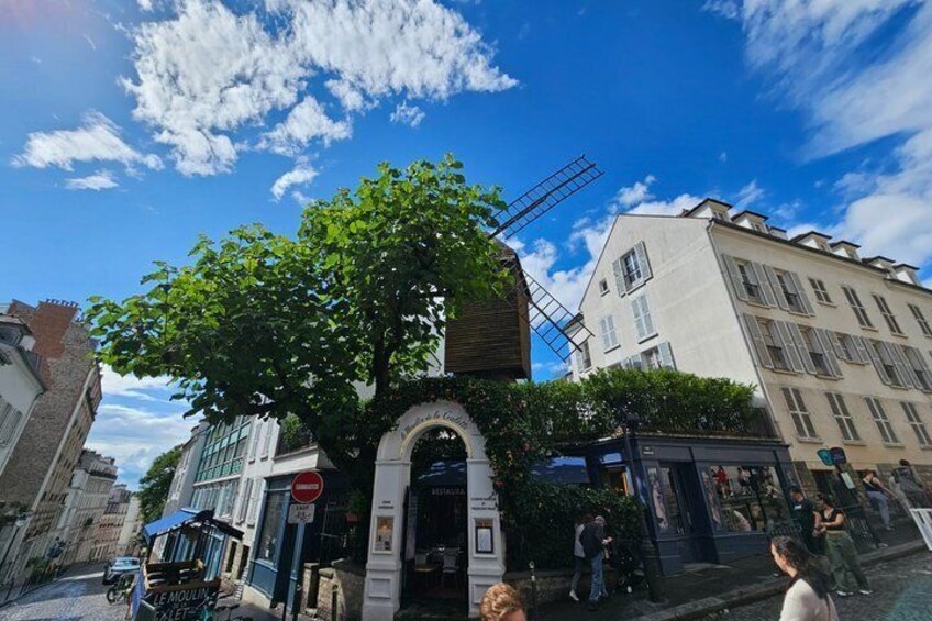 A tree-lined street with a building entrance, a sign, and a clear blue sky. 3