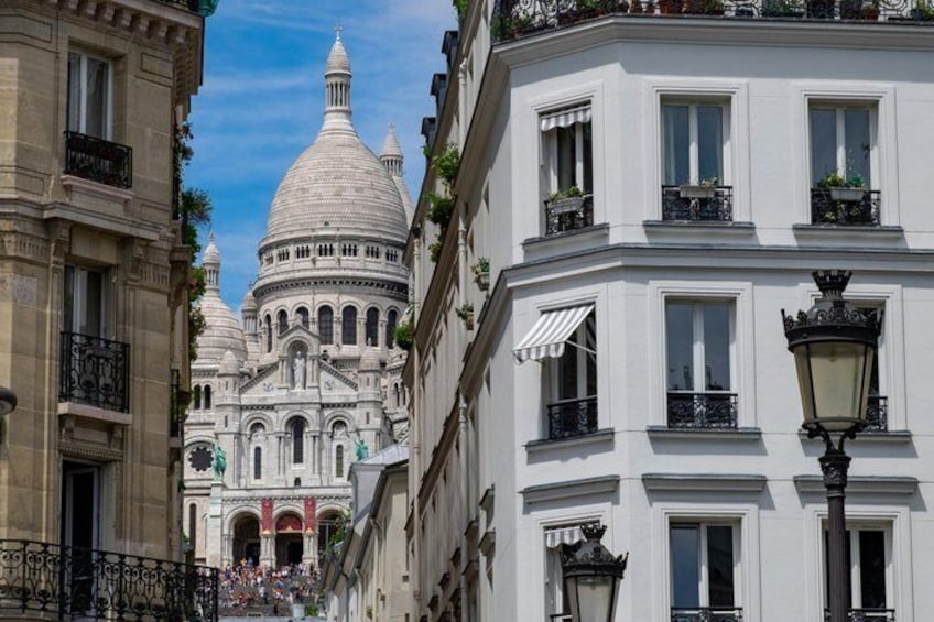 A street with classical architecture, including a domed building and ornate balconies. 1