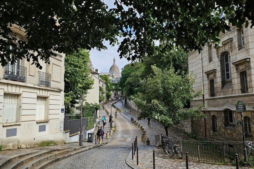 A cobblestone street lined with historic buildings, a dome in the distance, and bicycles parked along the side. 4