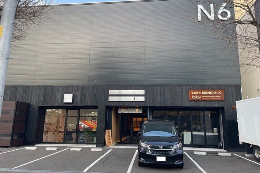 A building with a sign reading 'N6' and a parking lot with a black car. 4