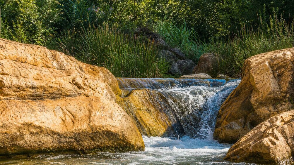 A waterfall cascading over large rocks in a forested area. 4