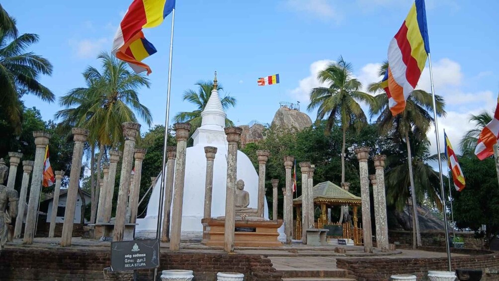 A temple complex with a central stupa, surrounded by stone columns and palm trees. 5