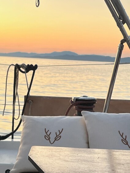 A boat with a table and cushions, a rope, and a sunset over water with distant land. 3