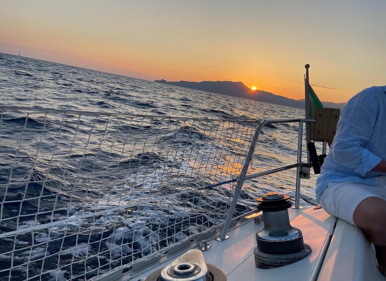 A boat at sea during sunset with waves and a flag. 4