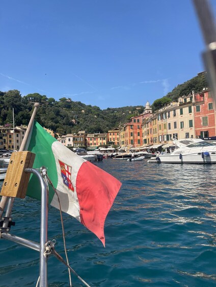 A flagpole with a flag, a body of water, and buildings in the background. 1