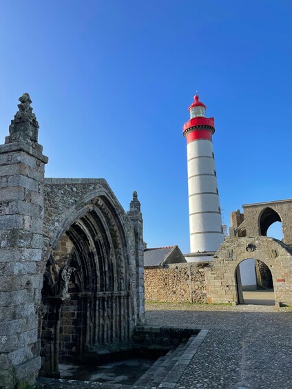 A historic stone archway, a lighthouse, and an old stone building. 2