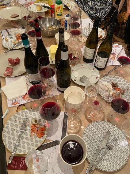 A table with wine bottles, glasses, plates with food remnants, and menus. 5
