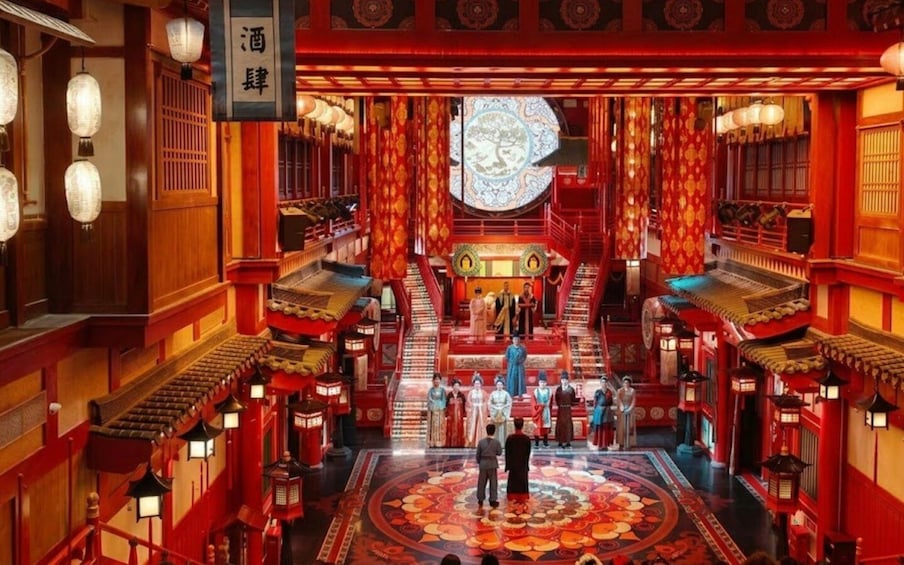 A traditional Chinese building with red and gold decorations, a large circular patterned floor, and a group of people in traditional attire. 3