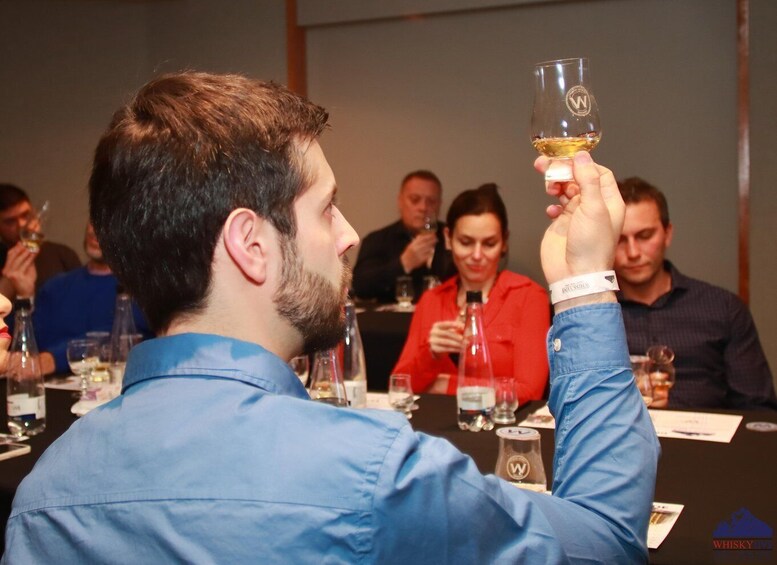A person holding a glass of whiskey at a social event. 4